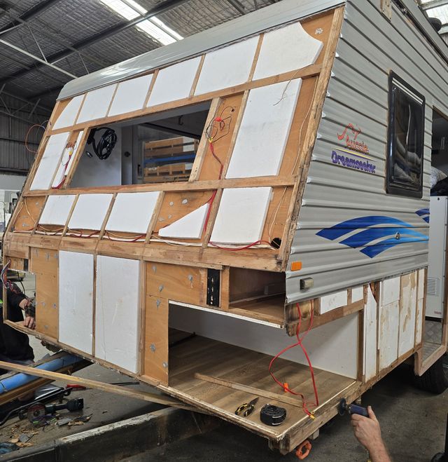 A man and a woman are painting a trailer.