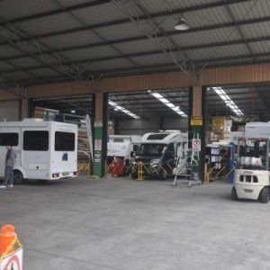 A warehouse filled with a lot of vehicles and a forklift.