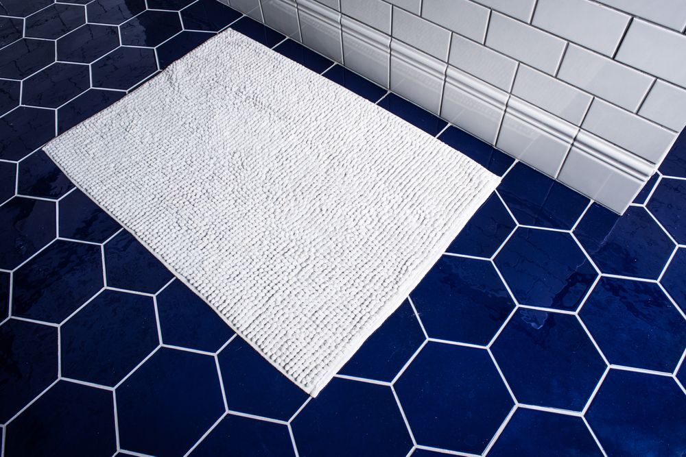 A white rug is sitting on a blue tiled floor