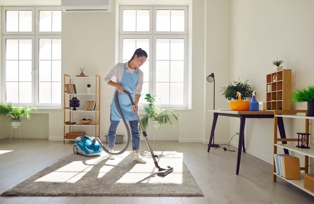 A woman is using a vacuum cleaner to clean a rug in a living room.