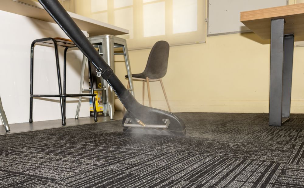 A vacuum cleaner is being used to clean a carpet in an office.