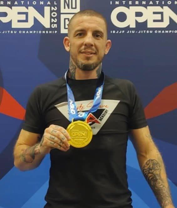 Man holding a gold medal in front of a Virginia Kids International Open backdrop