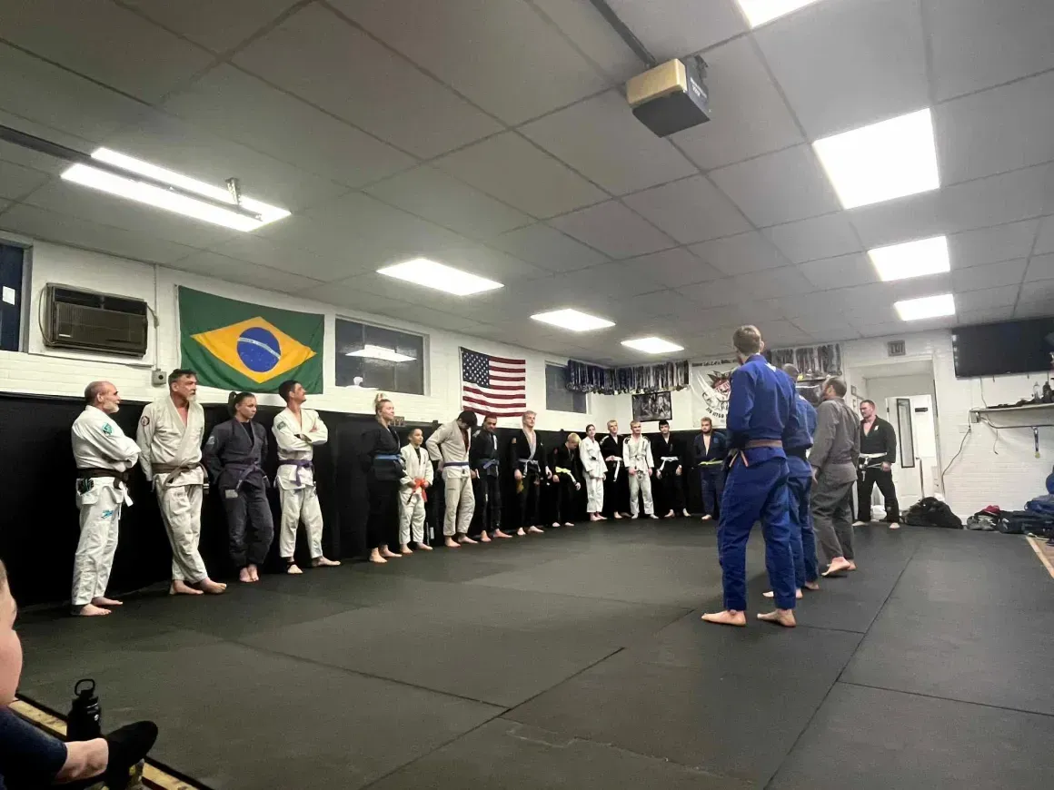 Martial arts class in gis lining up in Arte Suave in Beckley, WVwith instructors in blue and flags on the wall.