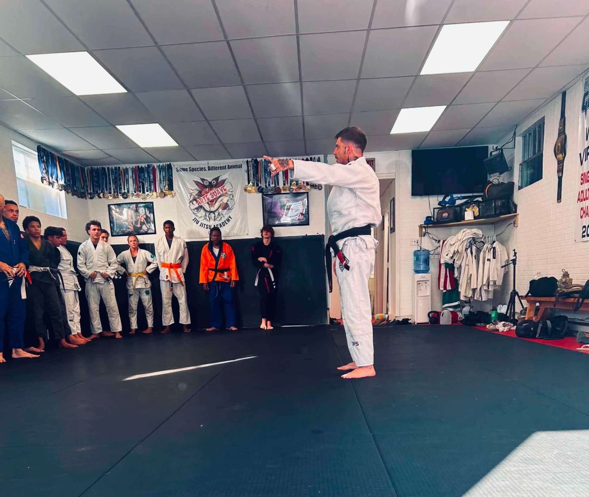 Martial arts class in Arte Suave in Beckley, WV instructor in white gi demonstrating a move while students watch.