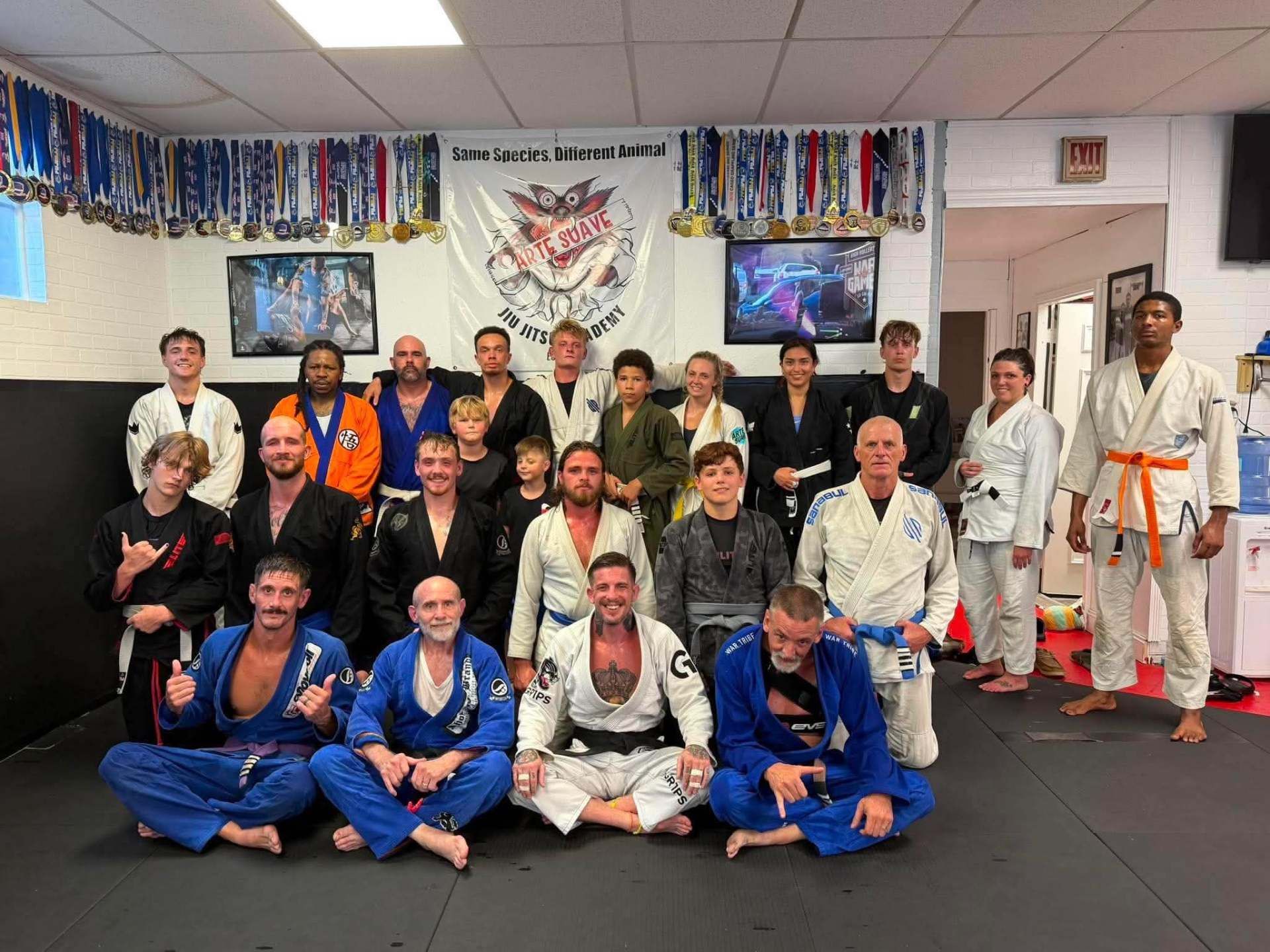 Group photo of martial arts practitioners in gis posing in Arte Suave in Beckley, WV with flags and banners on the wall