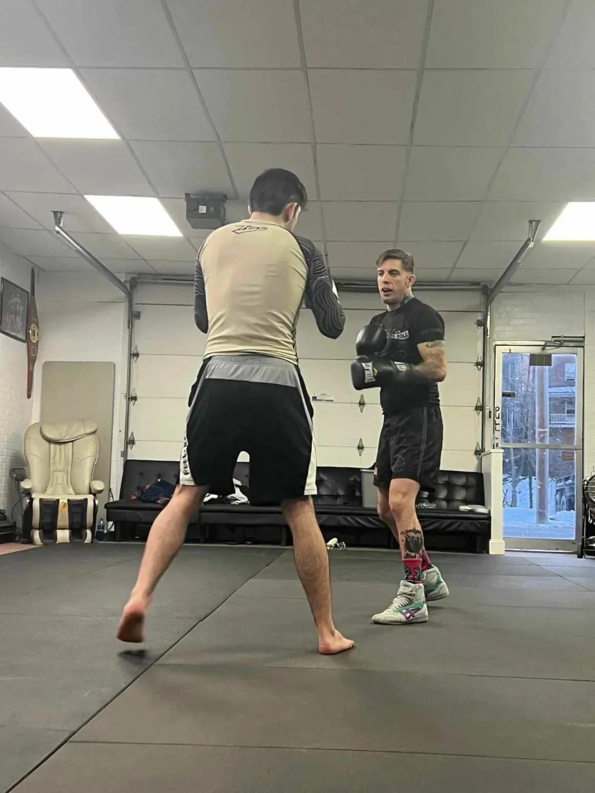 Two people sparring in Arte Suave in Beckley, WV, wearing boxing gloves on a padded mat