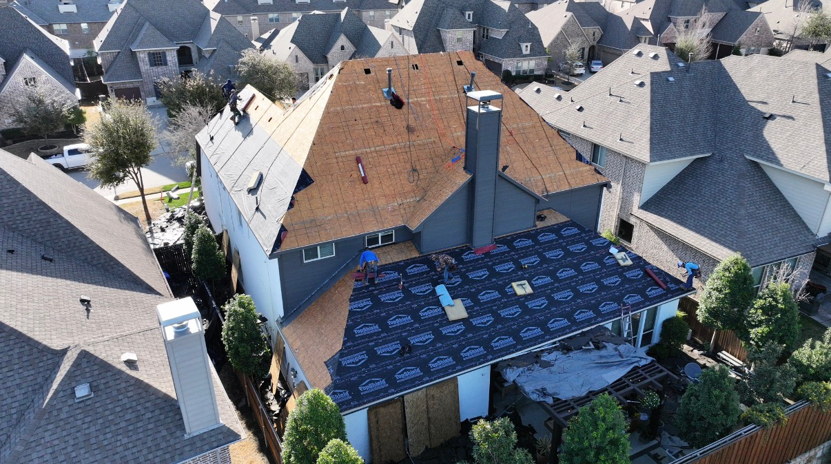 An aerial view shows a residential roof undergoing repair, with sections featuring new black underlayment and bare wood.