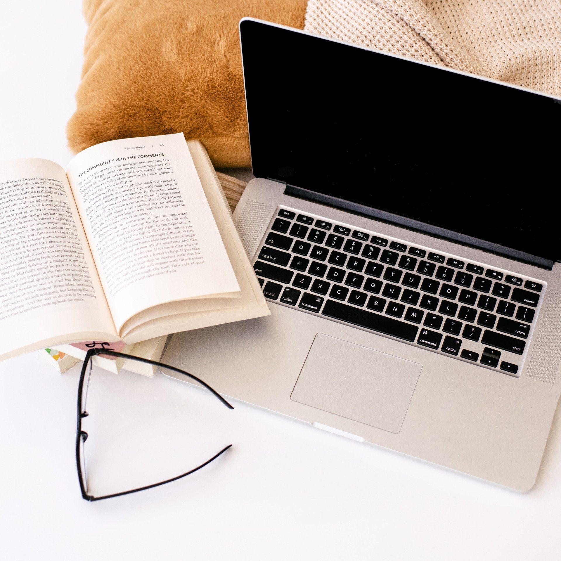 A laptop is open next to a book and glasses