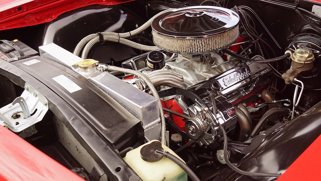 Red car engine with chrome details and an aluminum radiator.