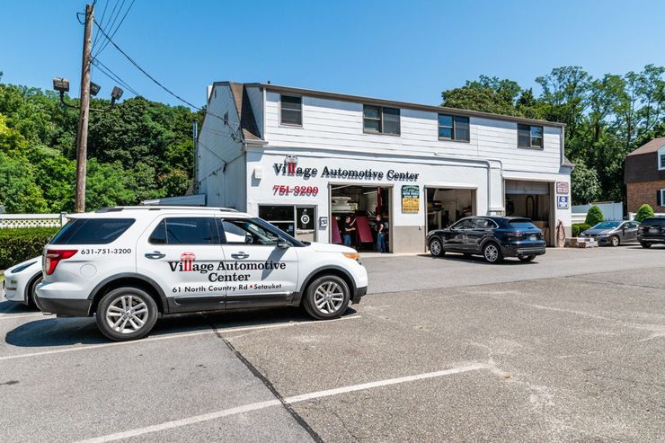 SUV in front of a white village insurance office with a black car parked beside it