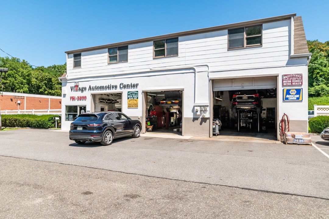 Exterior of Village Automotive Center with a blue Prius and red Fiat 500 parked outside.