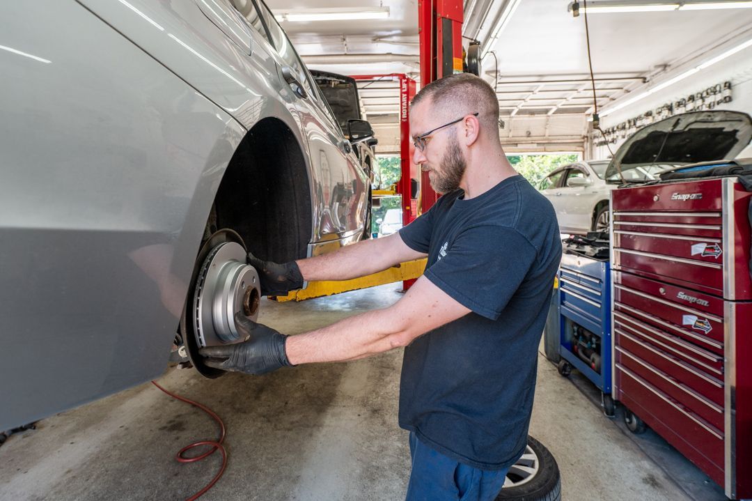 Mechanic using a power tool to work on a car wheel in an auto repair shop