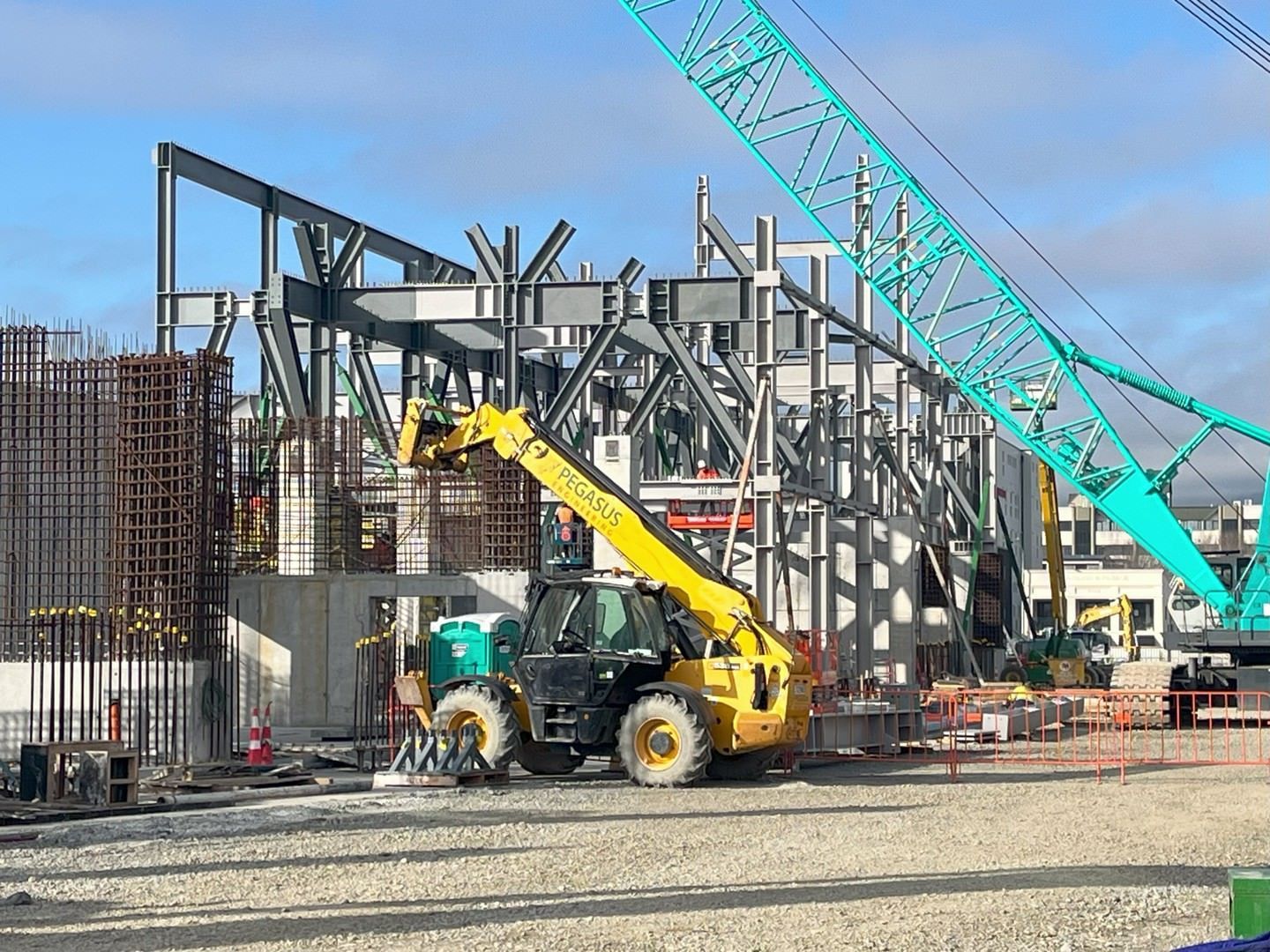 A construction site with a yellow tractor and a blue crane.