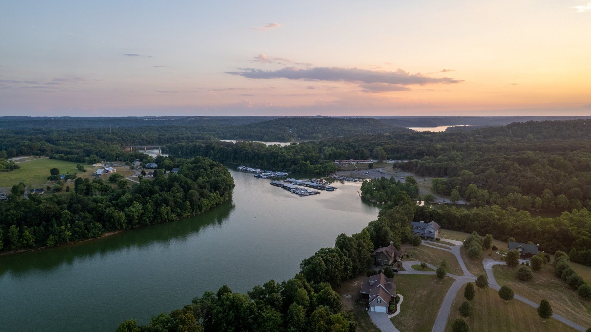 An aerial view of a lake surrounded by trees at sunset.