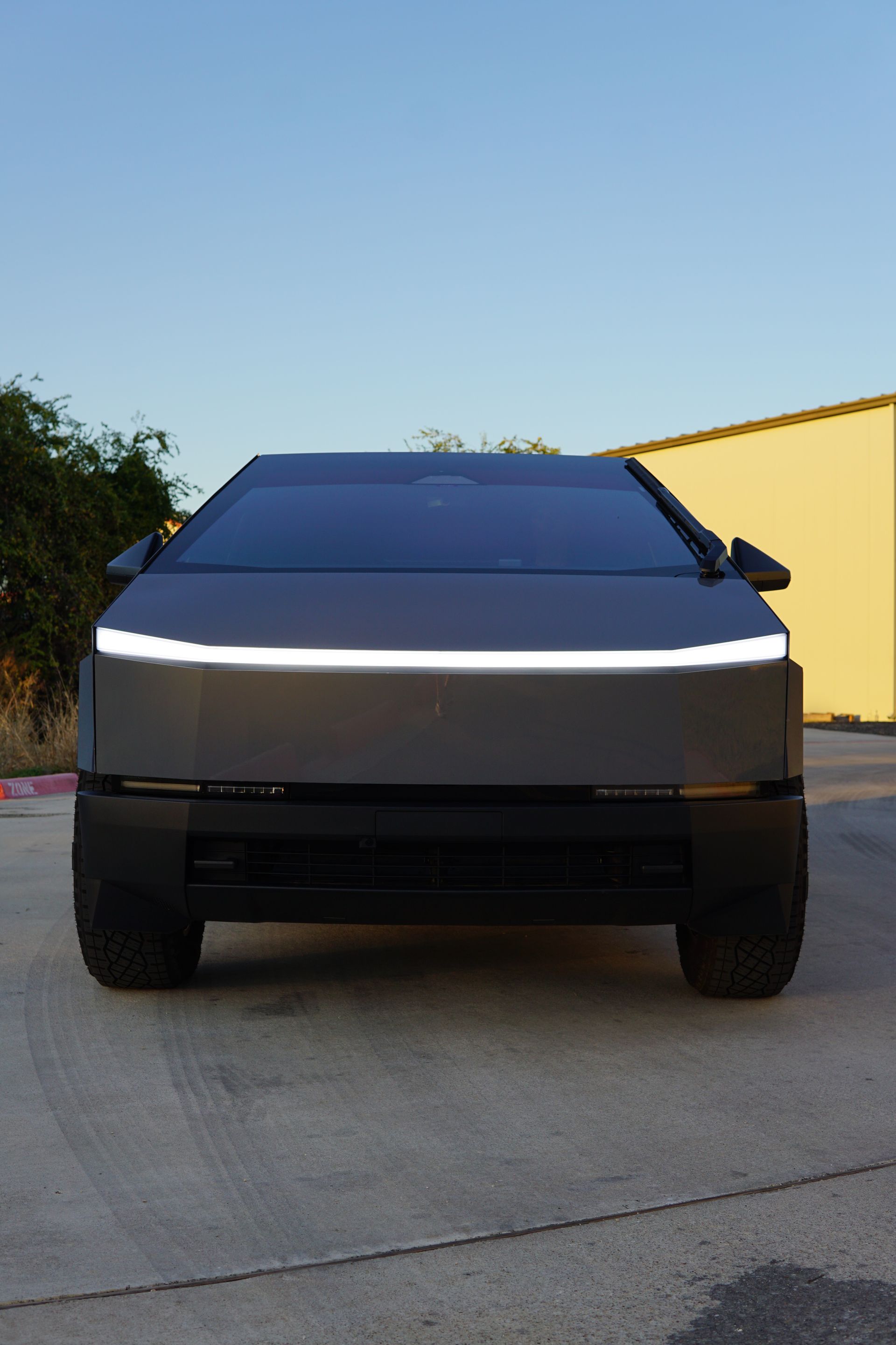 Front view of a silver Tesla Cybertruck parked on a driveway at dusk