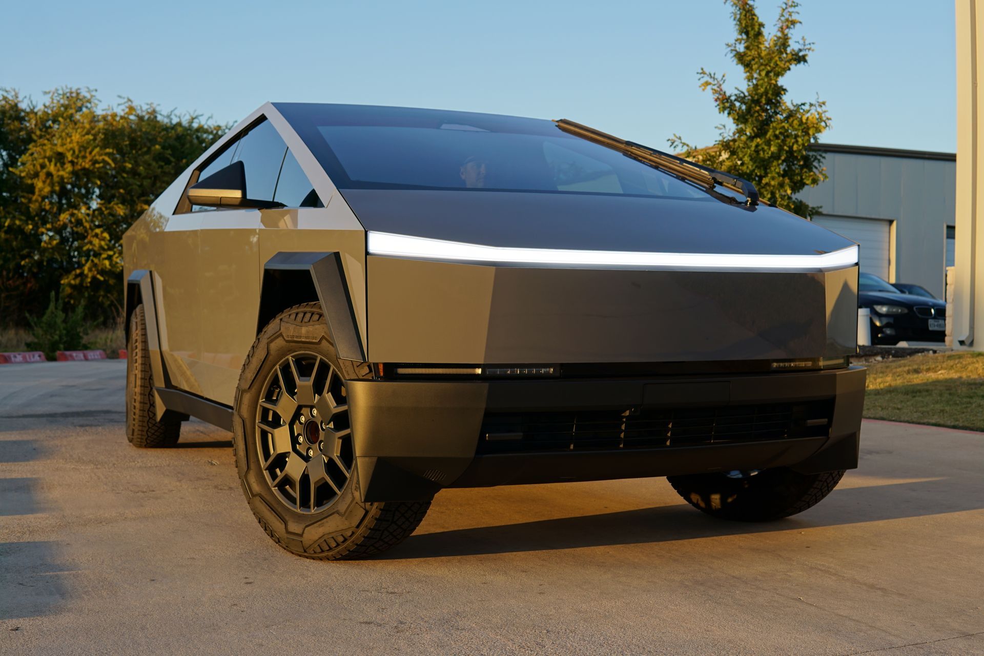 Silver Tesla Cybertruck parked outdoors in front of a building at sunset
