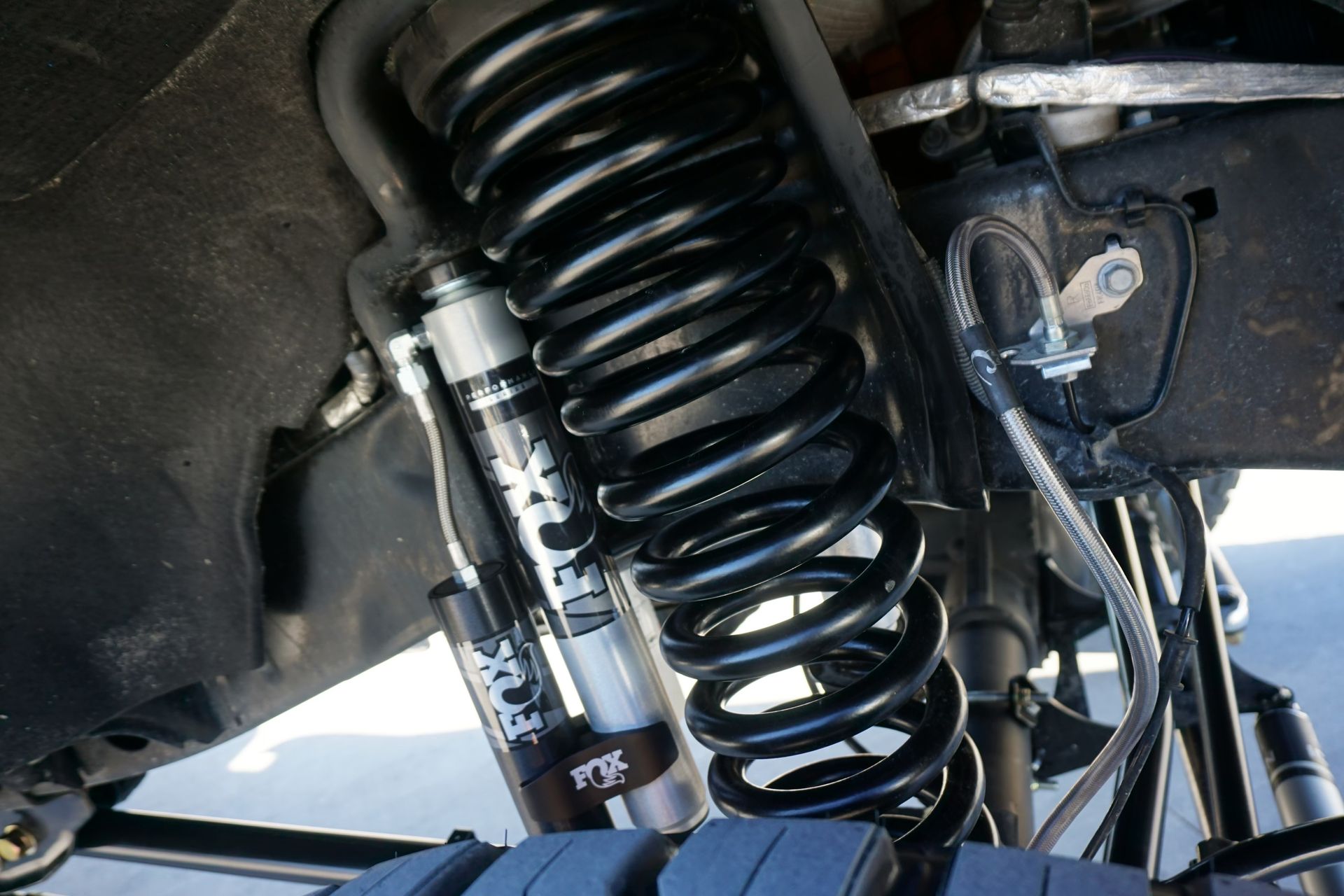 Close-up of a black suspension coil spring and shock absorber under a vehicle