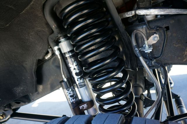 Red coilover shock absorbers with red springs on a black surface, close-up.