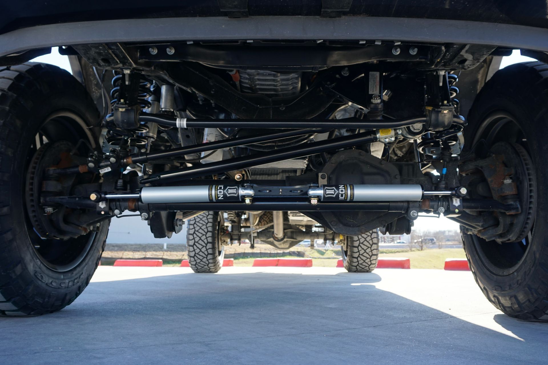 Undercarriage view of a vehicle showing the front axle, suspension, and steering components.
