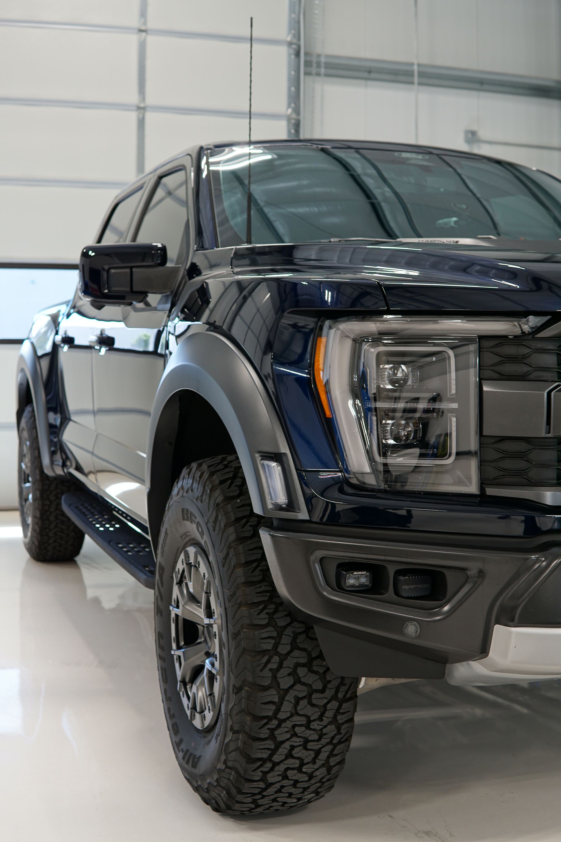 Black lifted pickup truck in a garage, front three-quarter view.