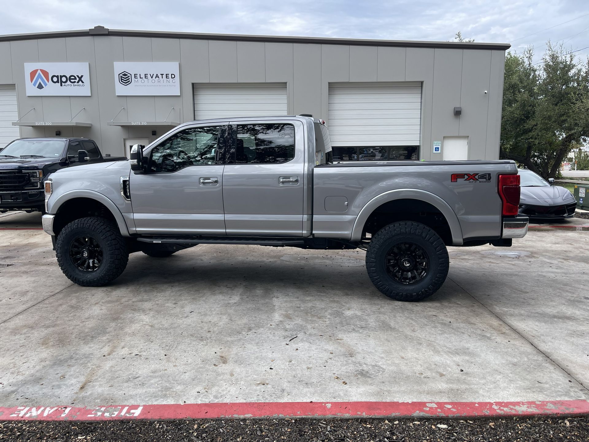 Silver lifted pickup truck parked outside an auto shop