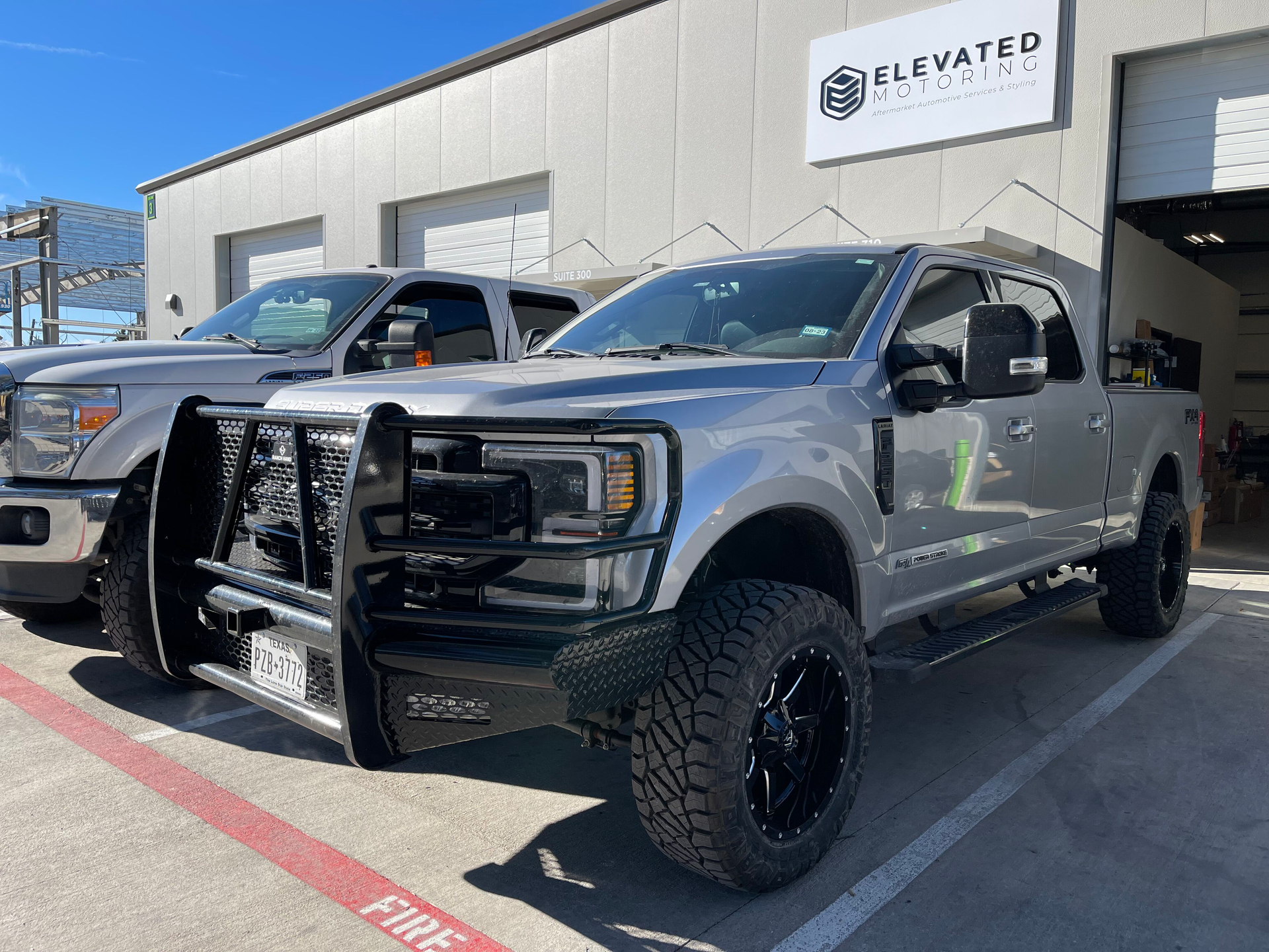 Gray pickup truck with black grille guard parked outside an auto shop