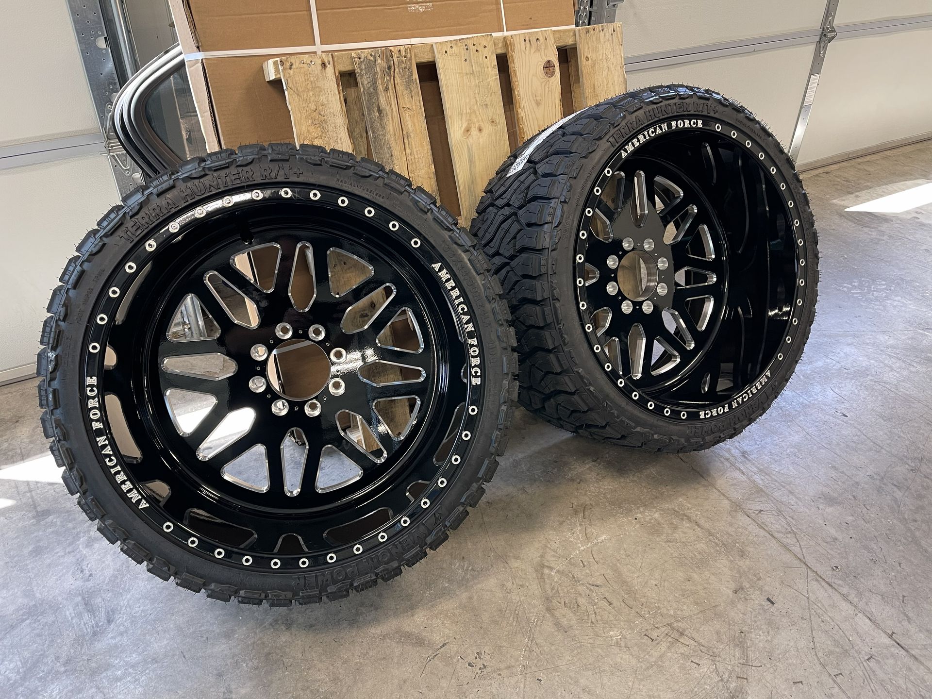 Close-up of a black truck wheel and tire on a white vehicle in bright daylight