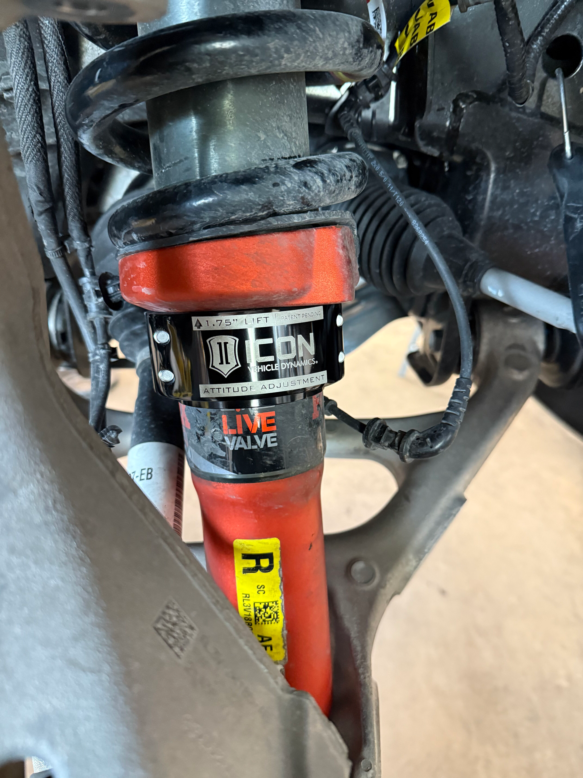 Close-up of a bicycle suspension fork and frame with black cables and an orange-red shock tube.