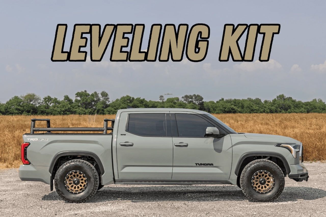 Gray pickup truck with “LEVELING KIT” text, shown in side view on a gravel lot.
