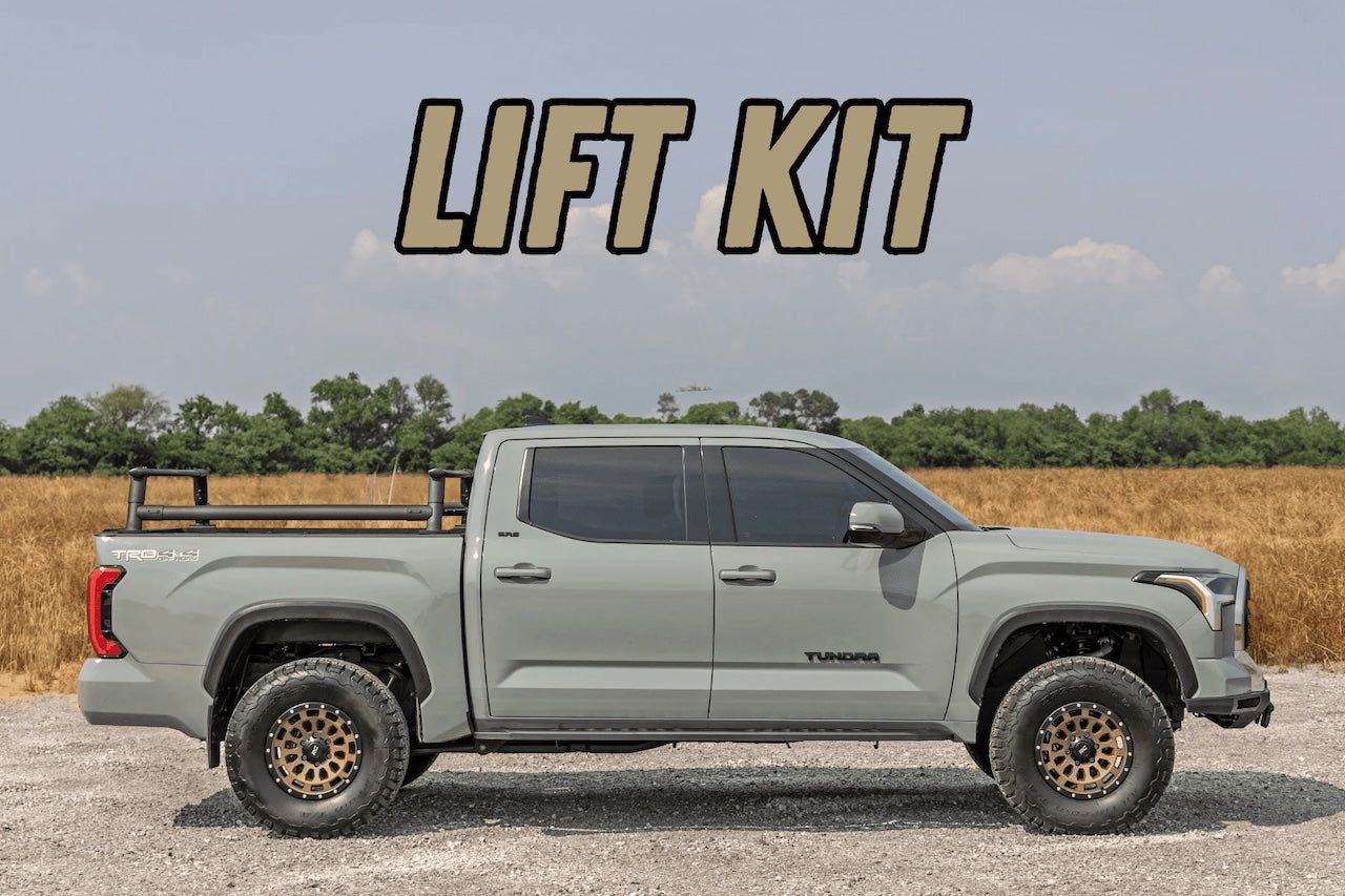 Gray pickup truck with a lift kit on a gravel road, with “LIFT KIT” text above.
