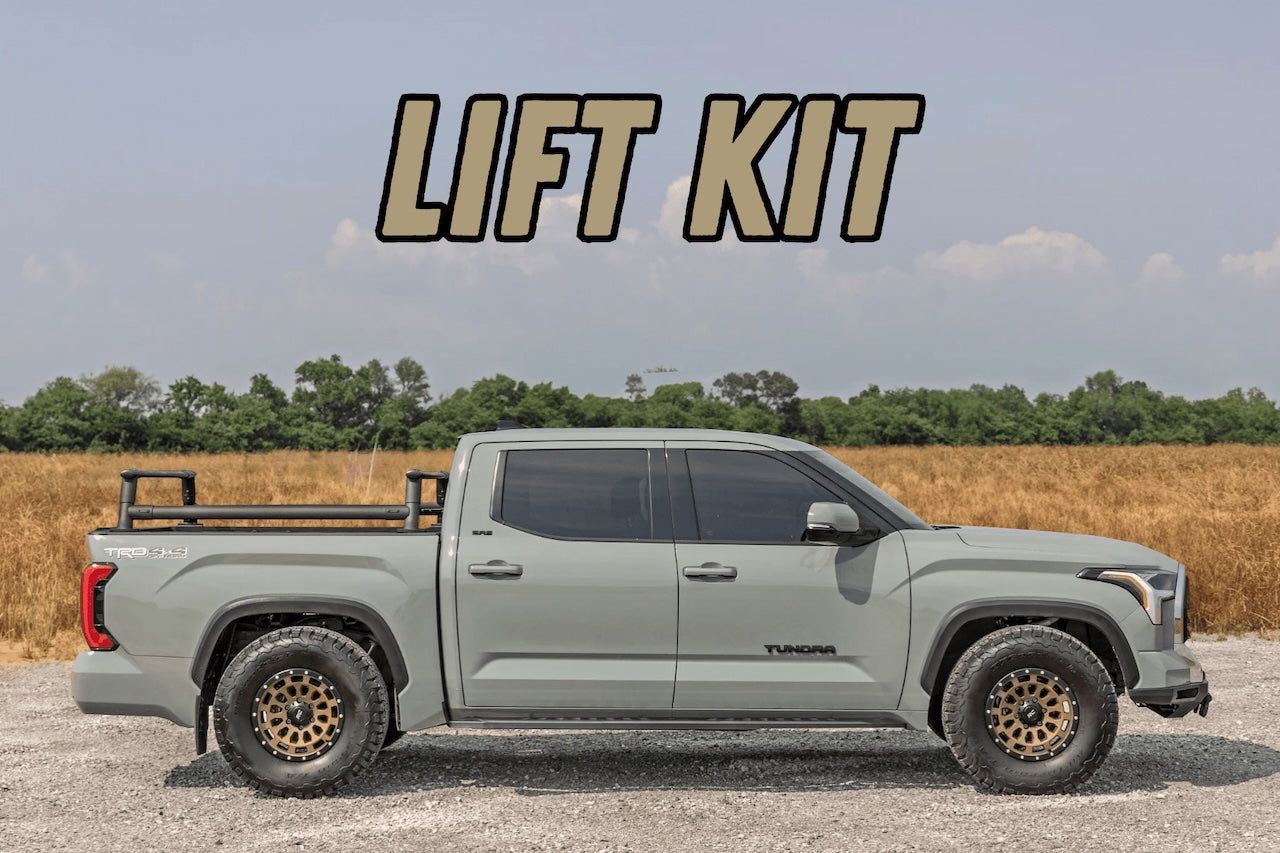 Gray pickup truck with lift kit parked on gravel under a cloudy sky