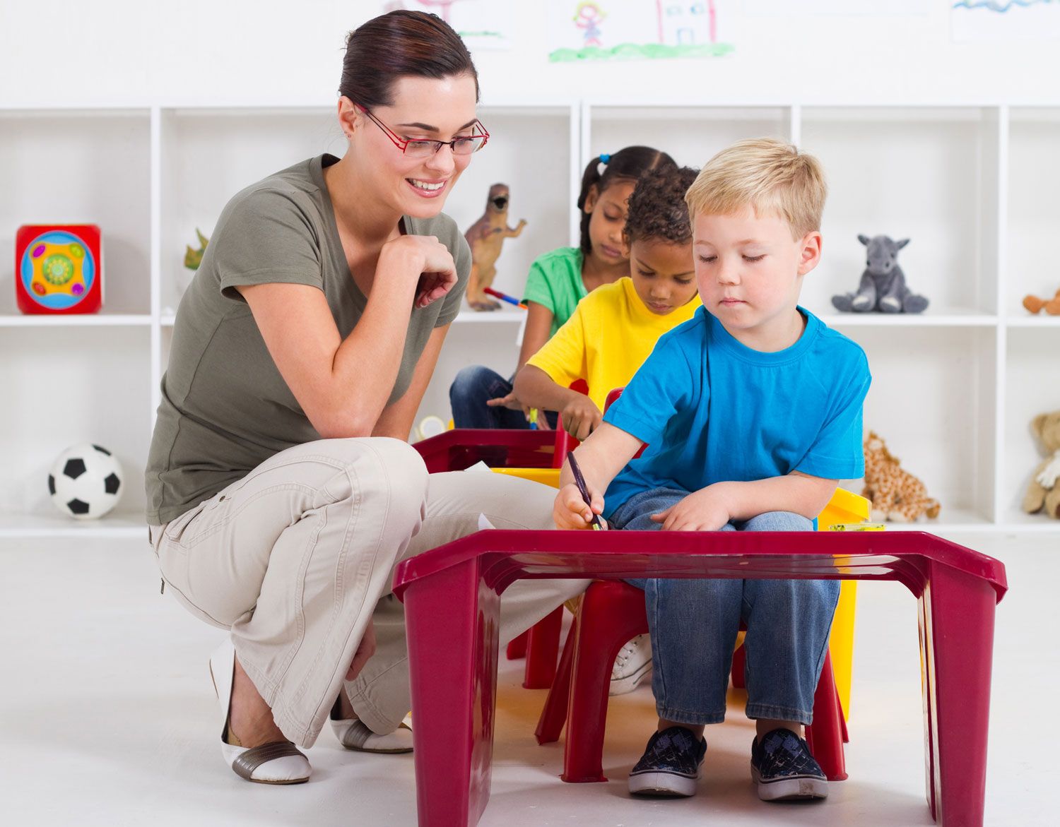 kindergarten teacher smiling while checking on students' work