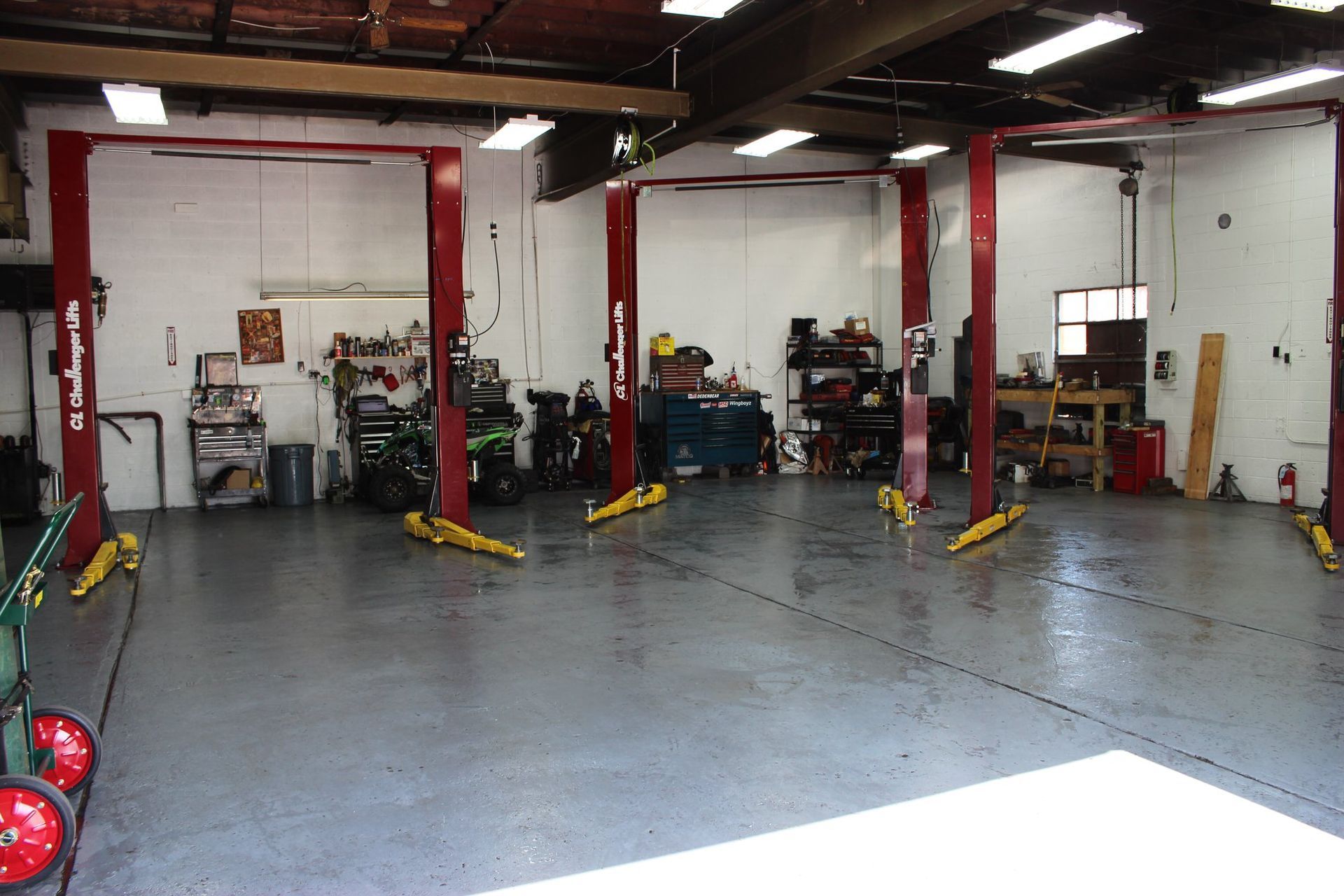 Interior of a car repair shop with several red car lifts and tools. | Your Buddy Steve's Garage
