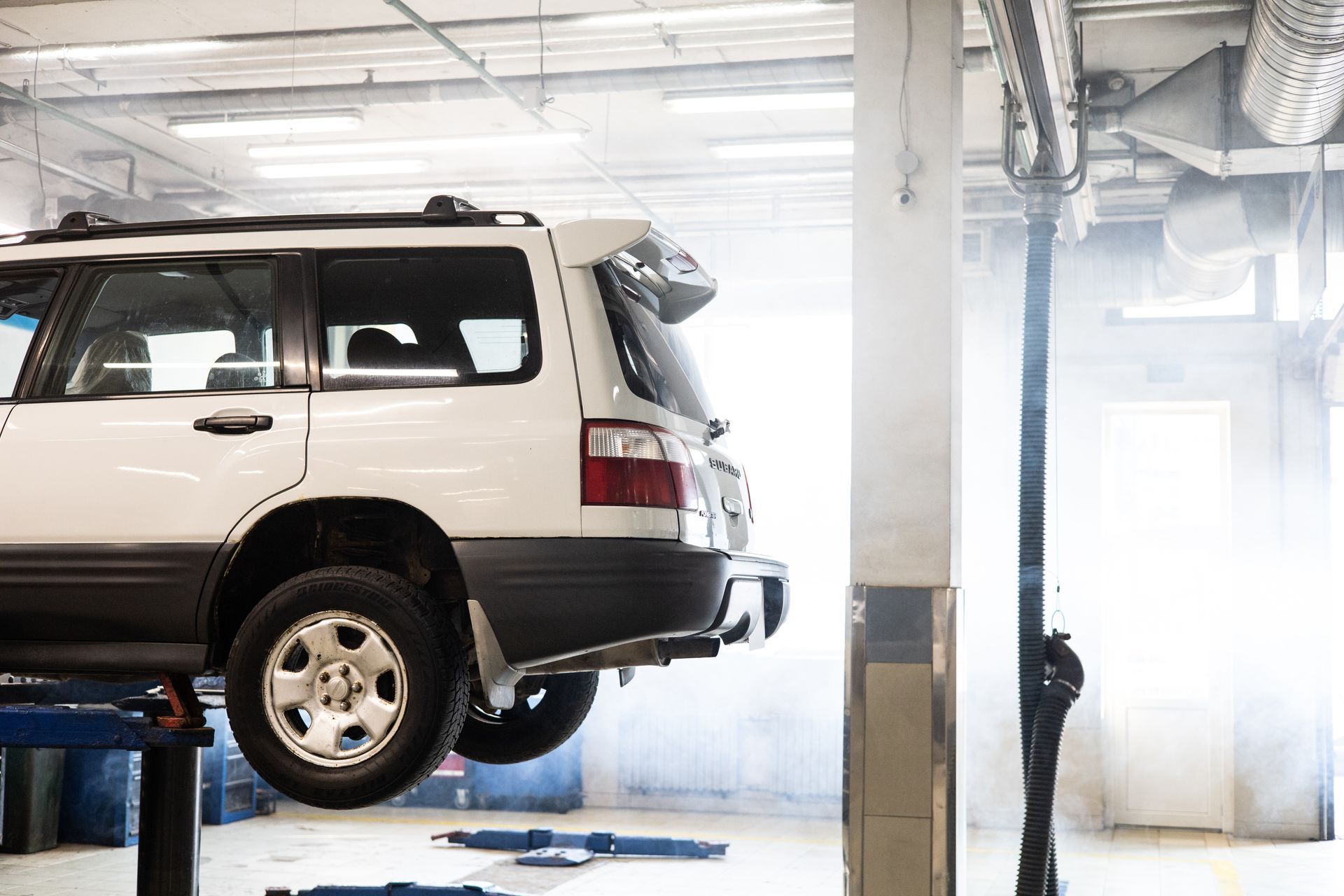 SUV raised on a lift in an auto repair shop, ready for a Pennsylvania state safety inspection and em