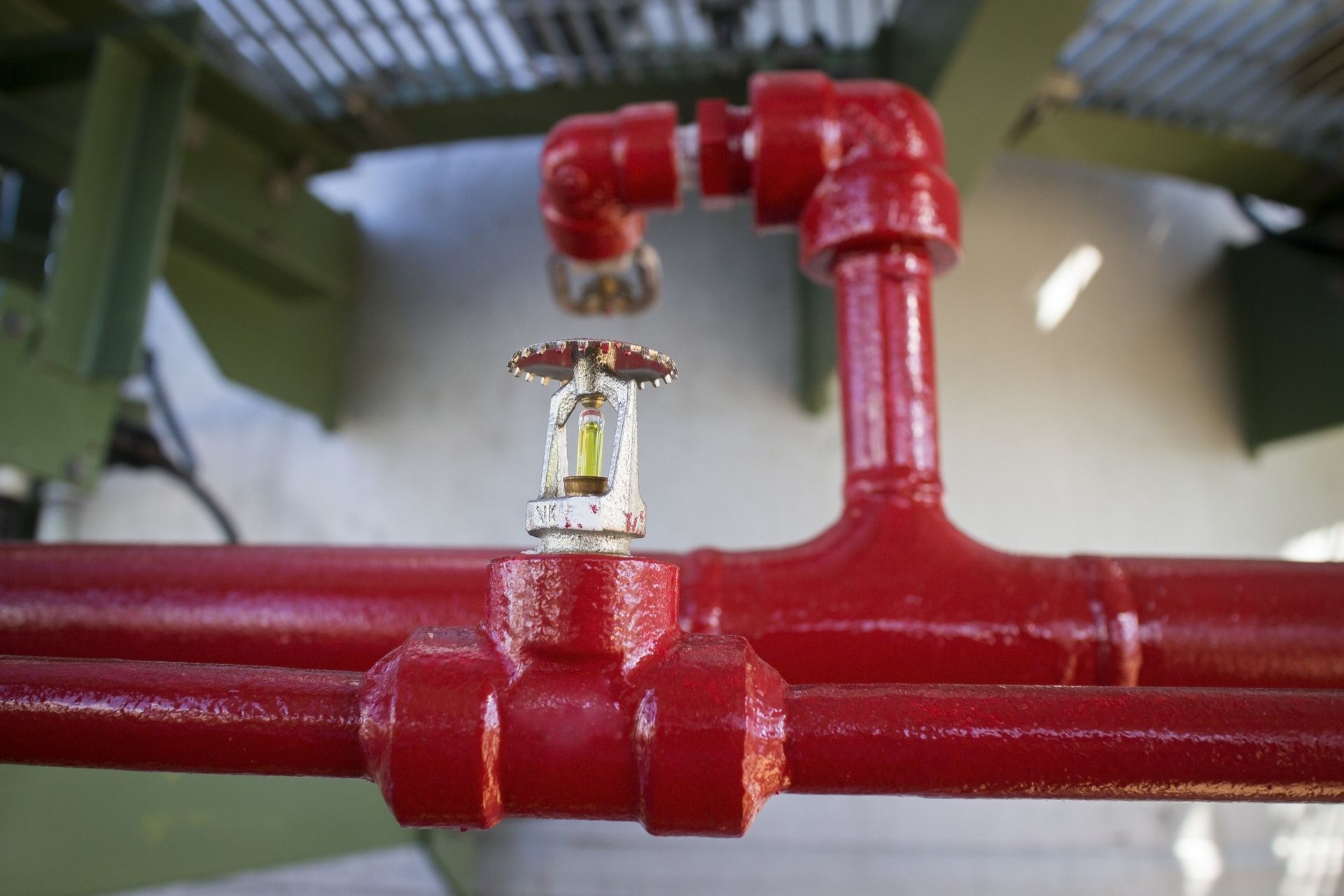 A close up of a fire sprinkler on a red pipe