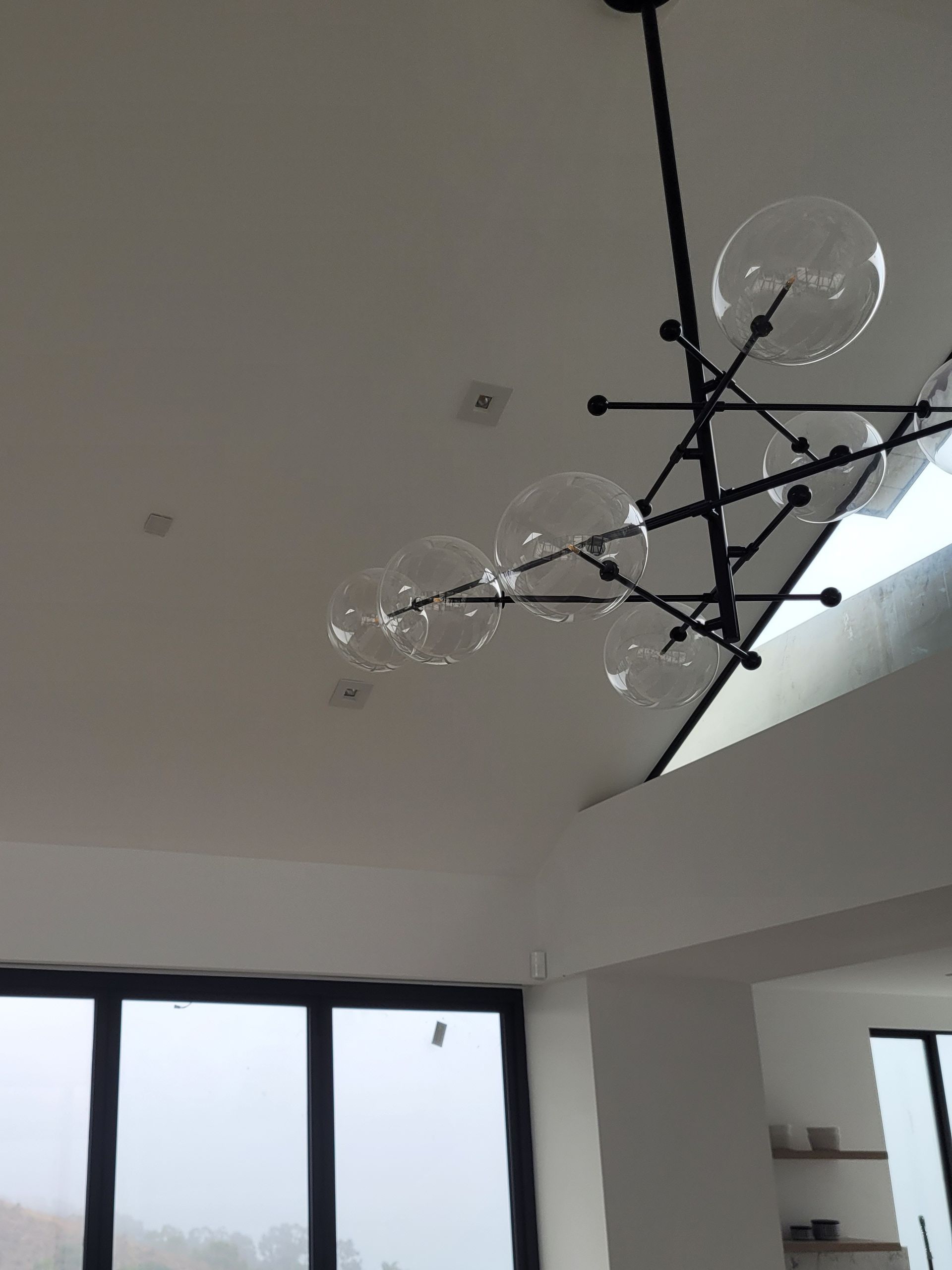 A chandelier is hanging from the ceiling in a room with a window.