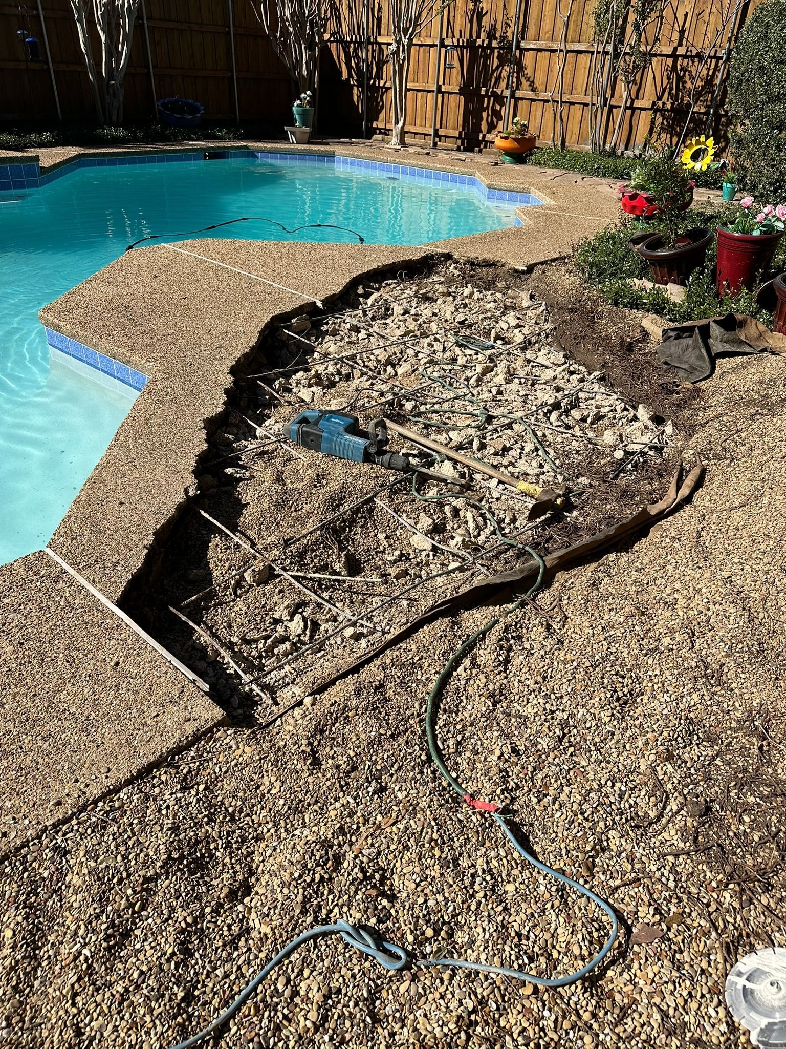 Poolside landscaping with gravel, a pool, and a hose.