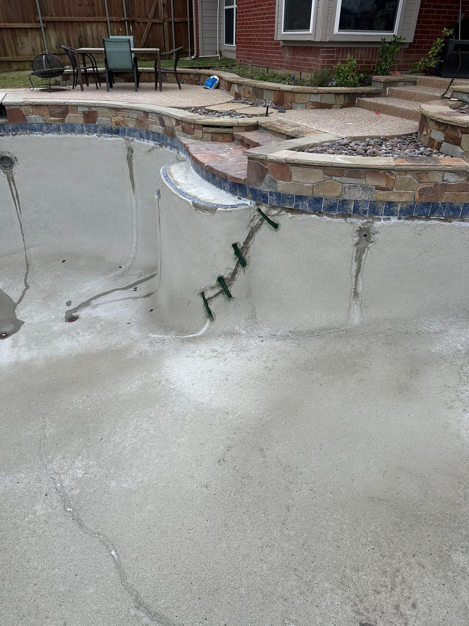Concrete pool under construction with visible cracks and supports.