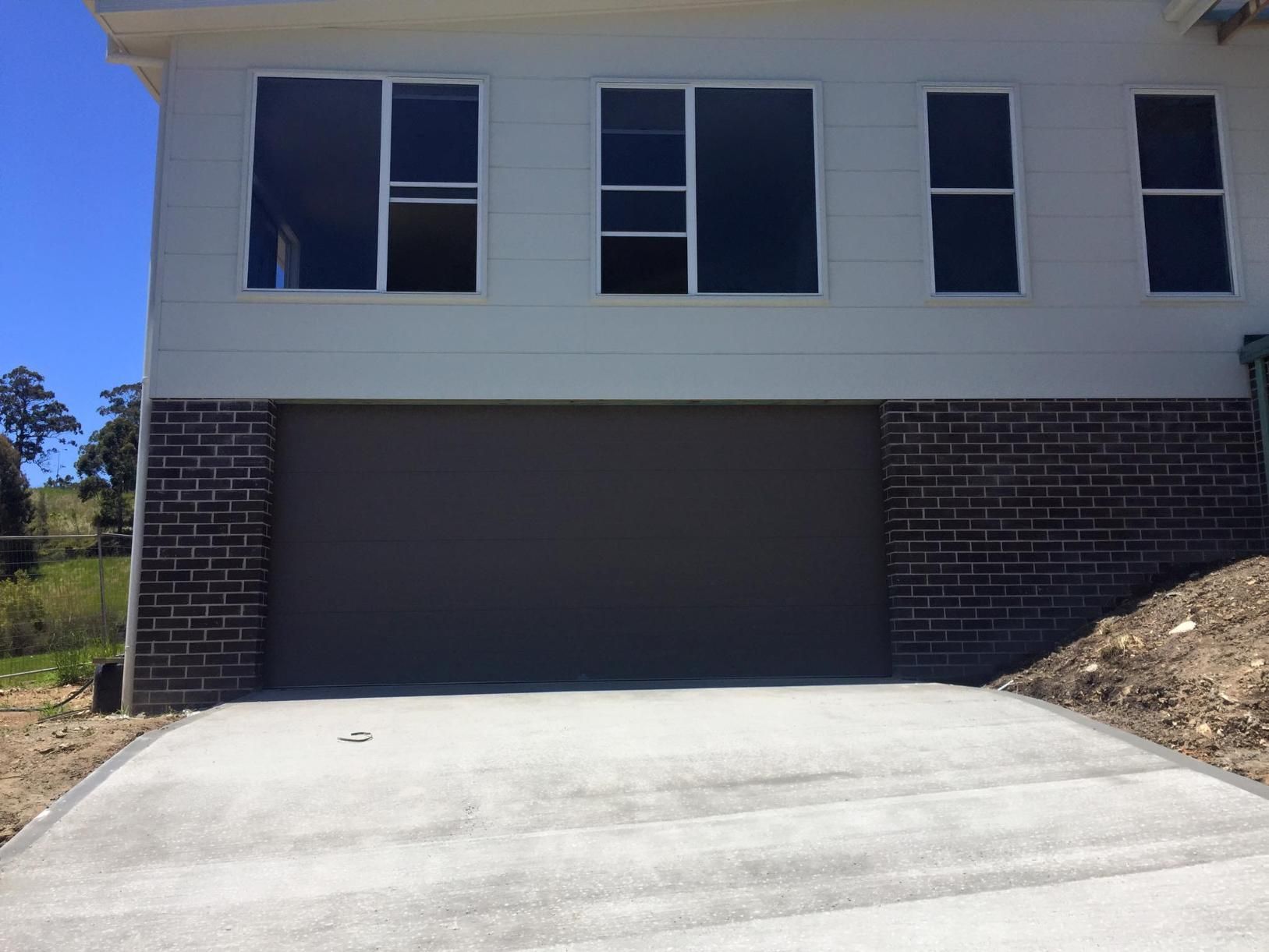 A House With a Black Garage Door and a Brick Facade — P & D Garage Doors in Laurieton, NSW