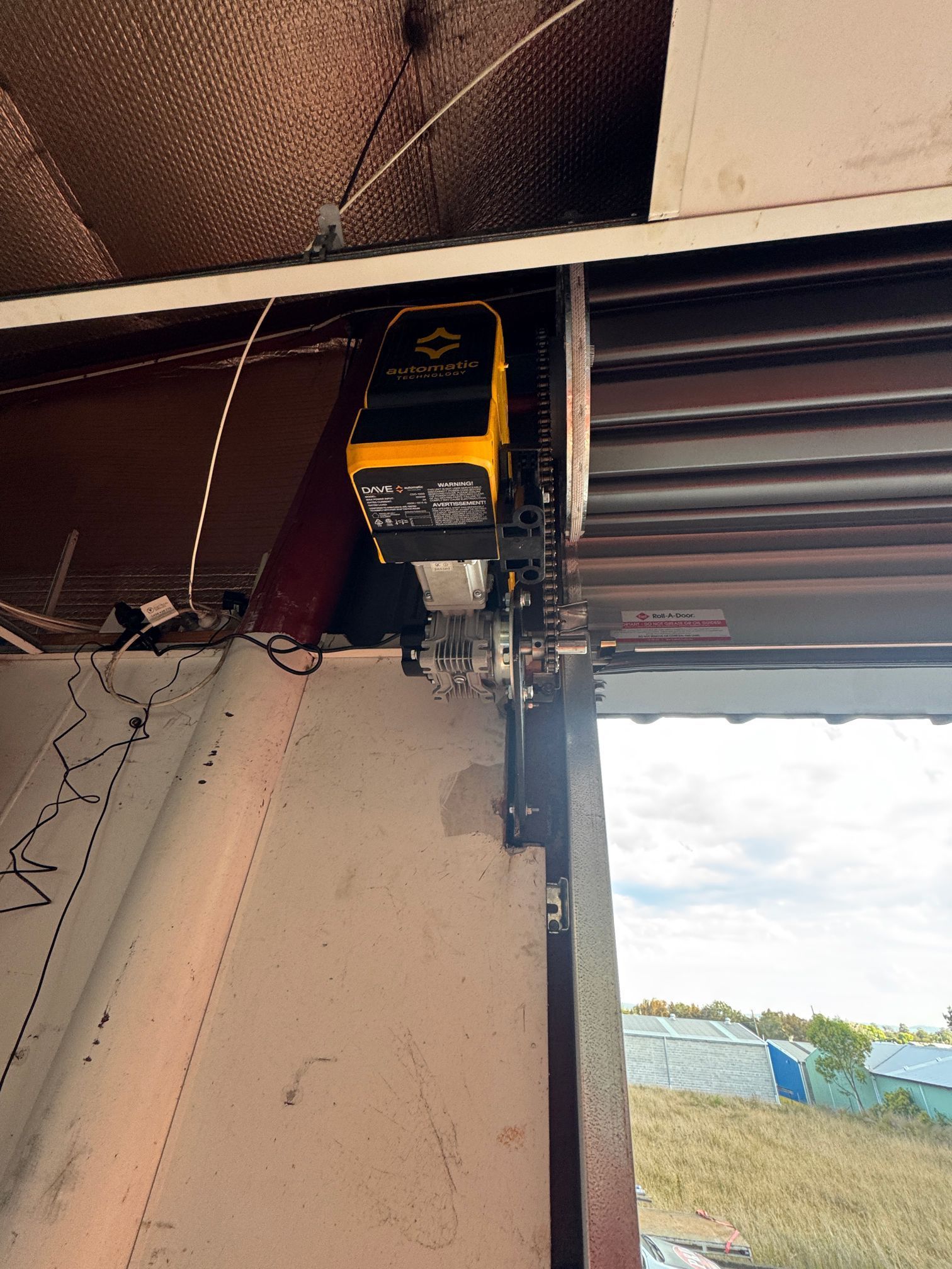 Yellow Garage Door Opener Mounted On A Ceiling Beam — P & D Garage Doors in Taree, NSW