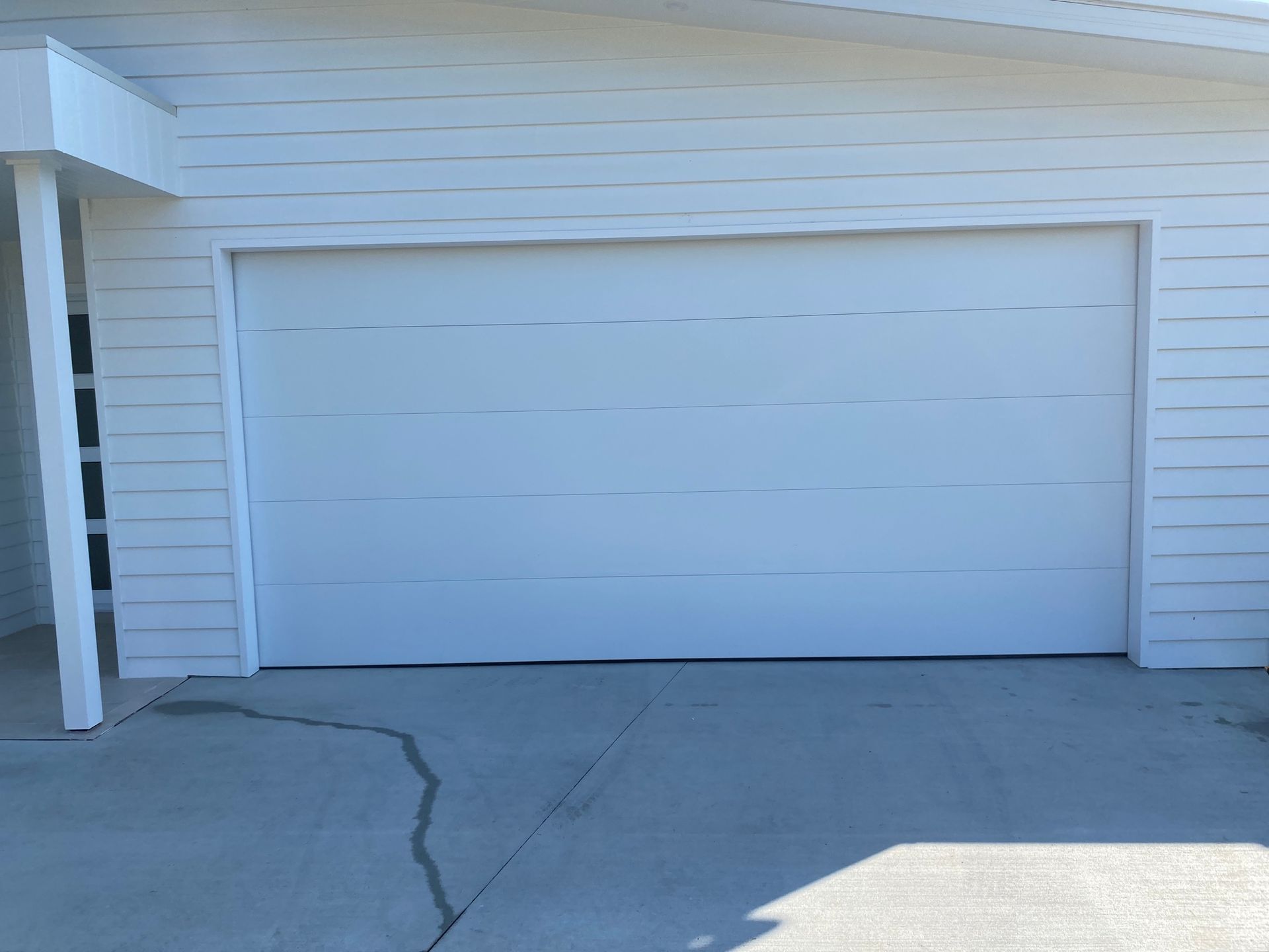 A white garage door is in front of a white house. — P & D Garage Doors in Harrington, NSW