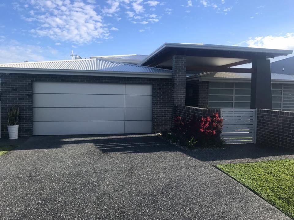 A Modern House With a Large Garage Door and a Driveway — P & D Garage Doors in Taree, NSW
