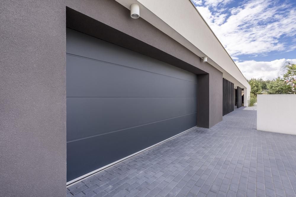 A Large Gray Garage Door is Sitting on the Side of a Building — P & D Garage Doors in Gloucester, NSW