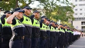 Agentes de policía uniformados saludando al aire libre.