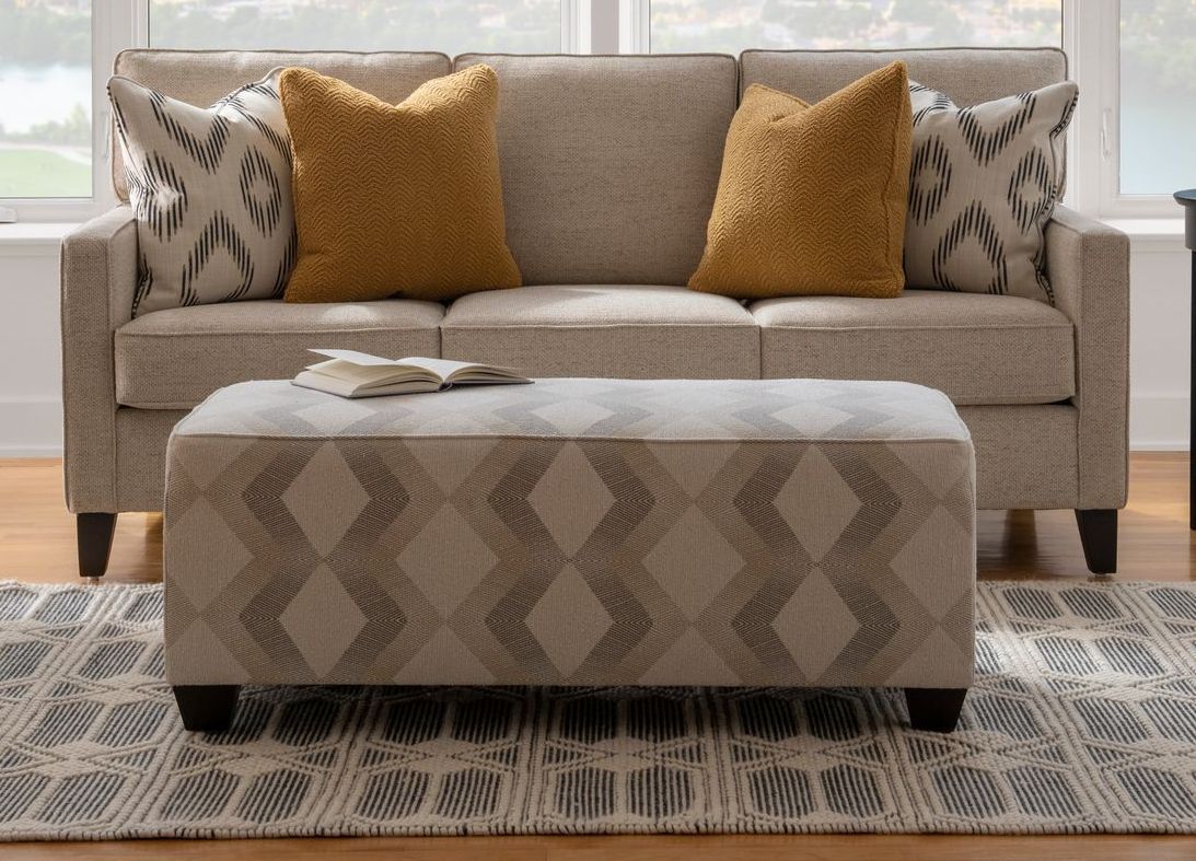 A living room with a couch , ottoman and rug
