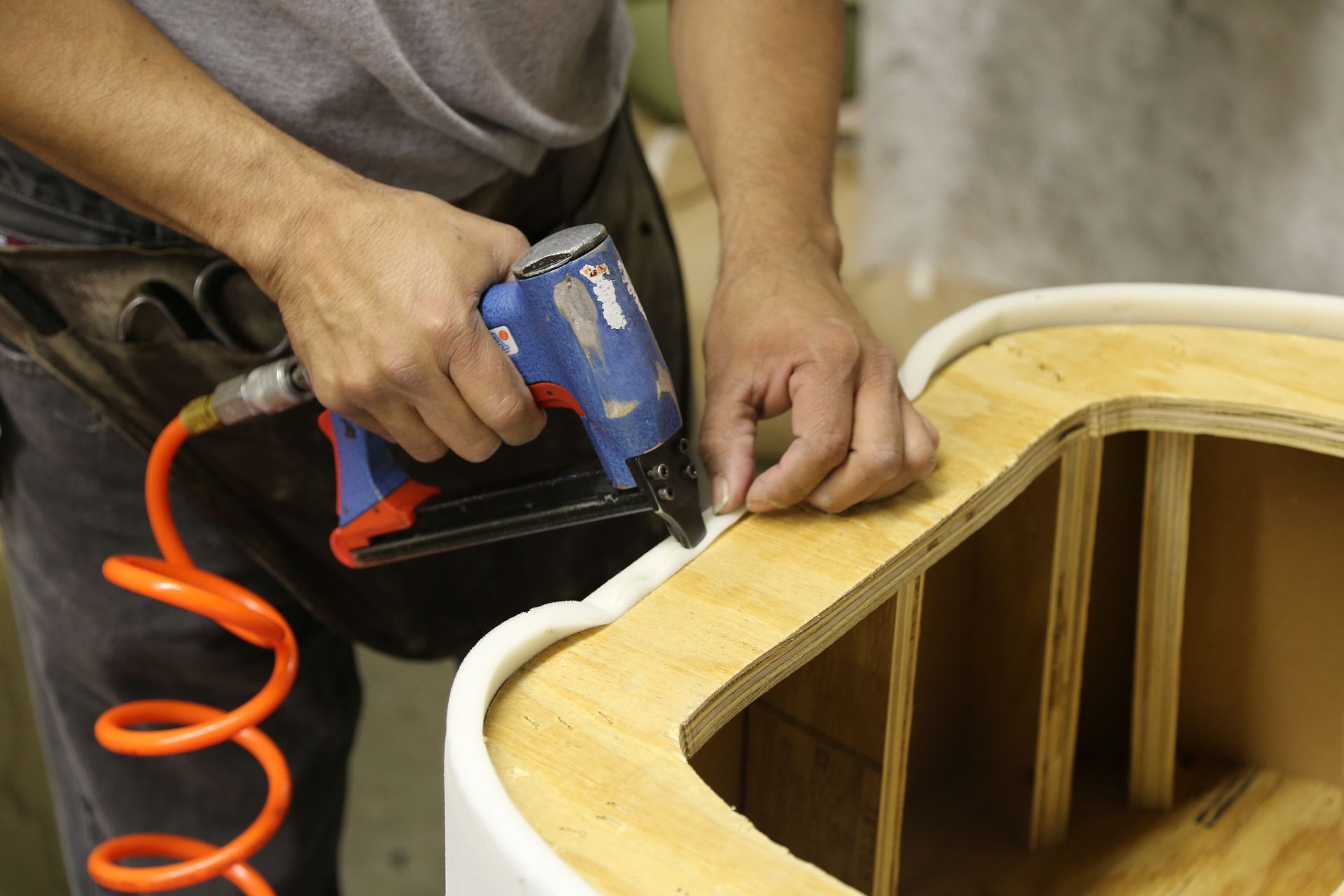 A man is using a stapler on a piece of wood