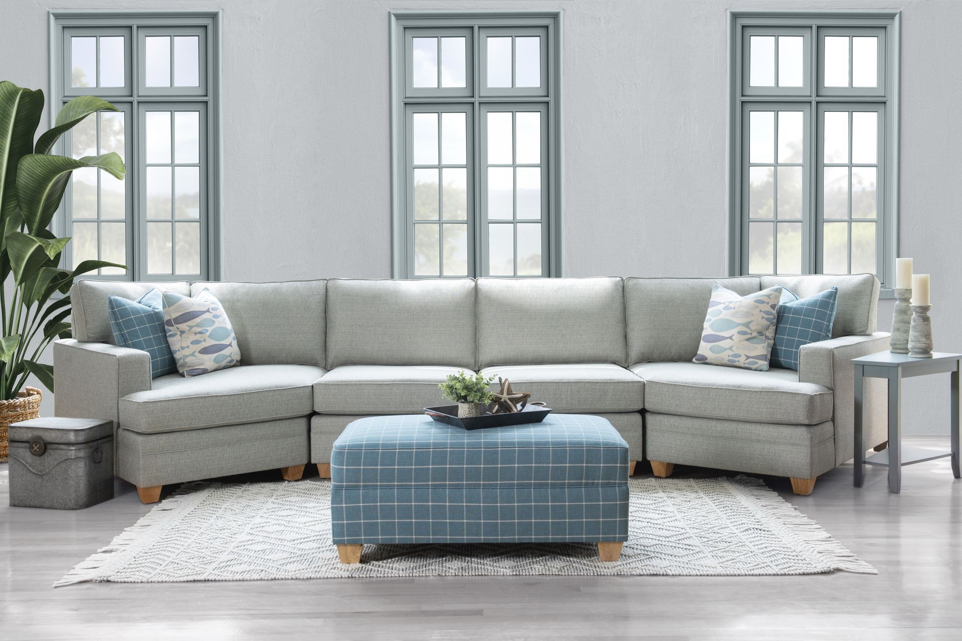 A living room with a large sectional couch and a blue ottoman. Izzy Sectional by JP Home
