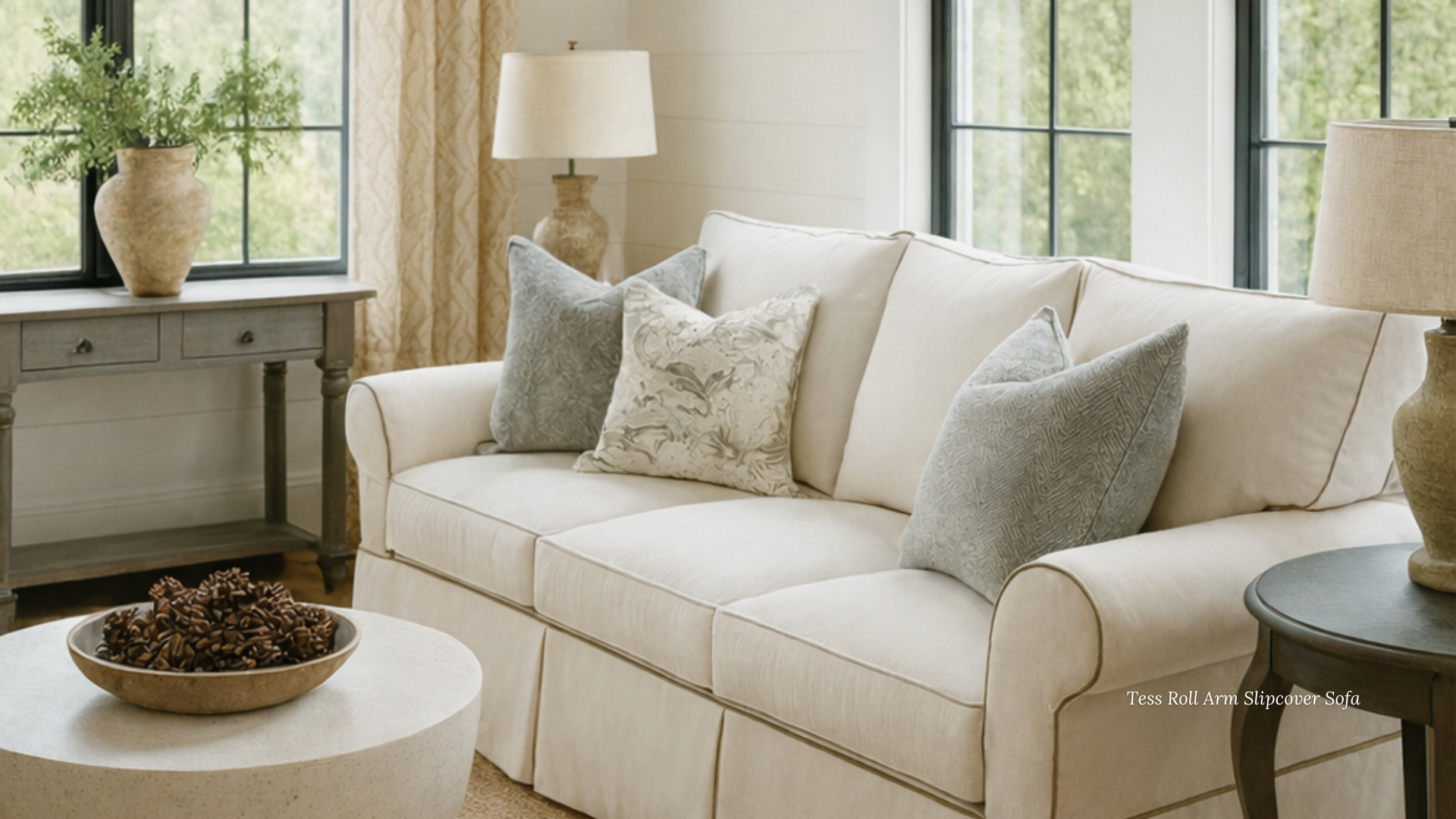 A living room with a white couch and an ottoman with a basket on top of it.