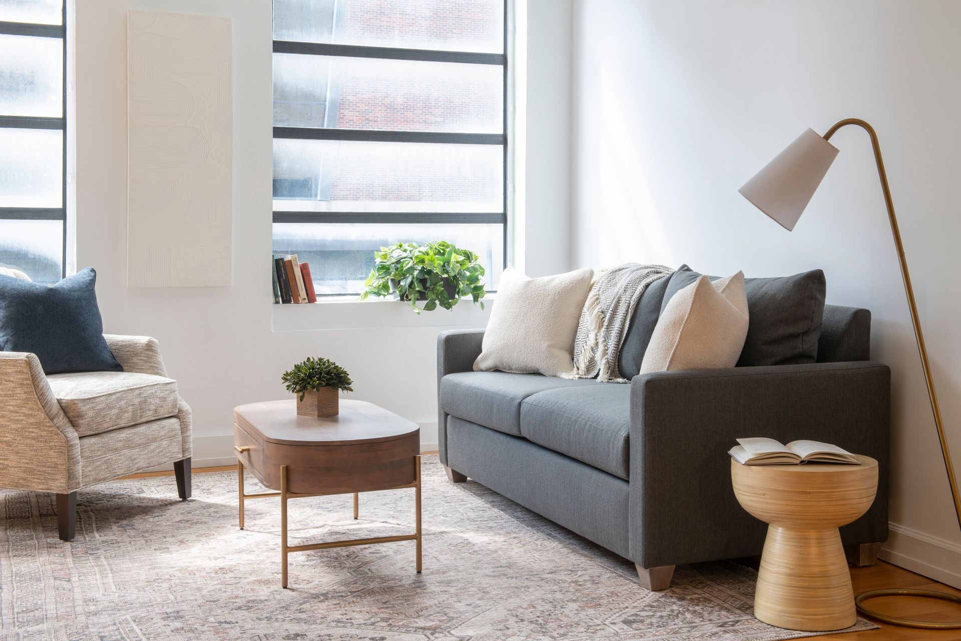 A living room with a couch , chair , coffee table and lamp.