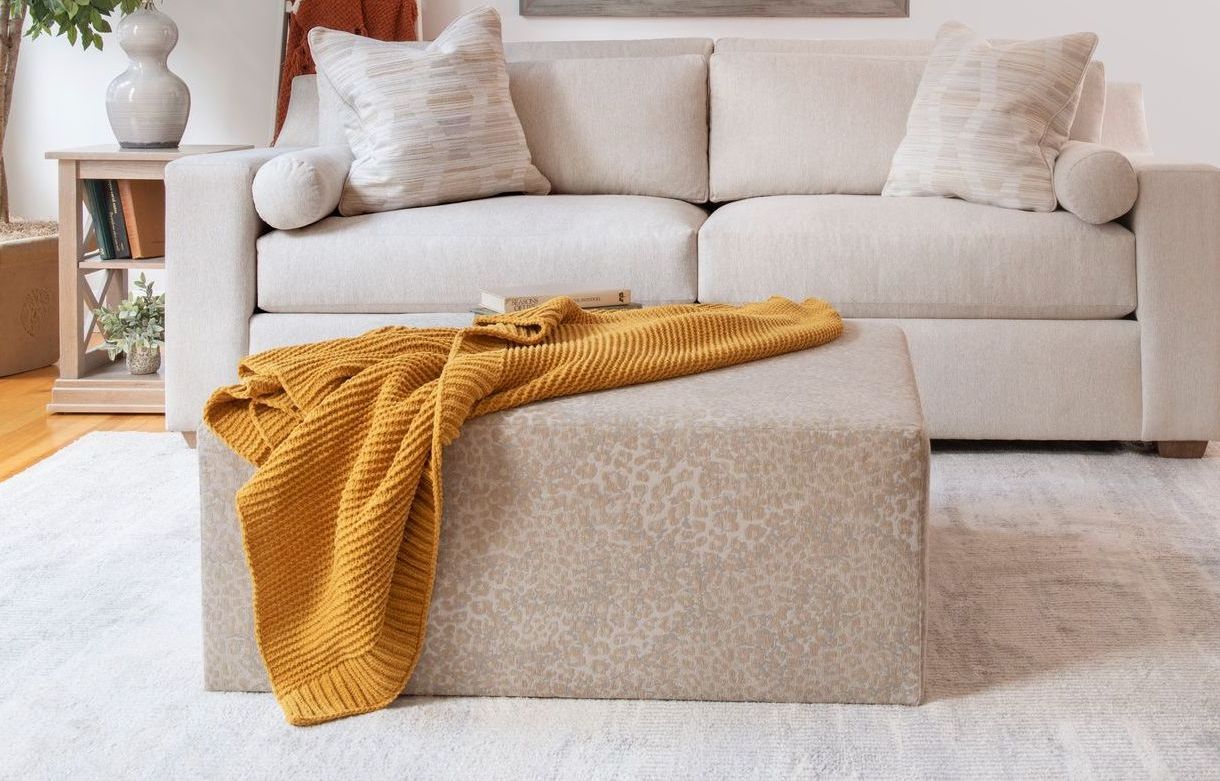 A living room with a couch , chair , coffee table and ottoman.